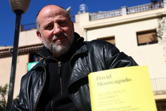 Pla contrapicat de l'escriptor David Monteagudo, amb el llibre 'Avui he deixat la fàbrica' desenfocat en primer terme. ACN