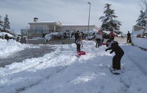 Pla general de diversos adolescents d'Ordal baixant per un carrer amb una taula d'snowboard mentre juguen amb la neu caiguda el 20 de març de 2018. AC