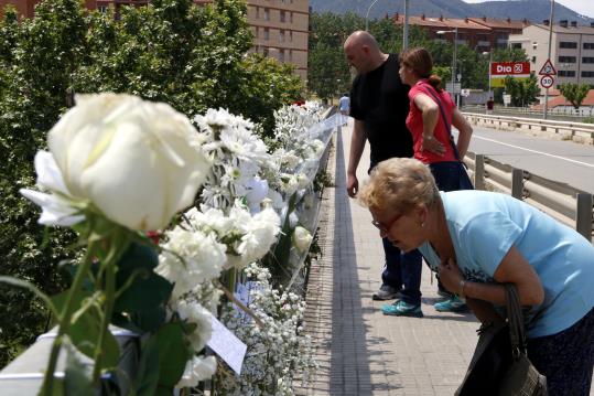 Pla general de la barana del pont on el jove va perdre la vida plena de flors blanques en record seu. ACN