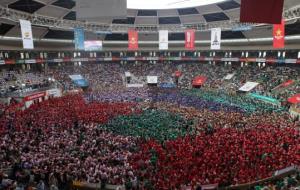 Pla general de la plaça Tàrraco Arena minuts abans de començar el Concurs de Castells de Tarragona, amb castellers vestits amb camises de tots colors.