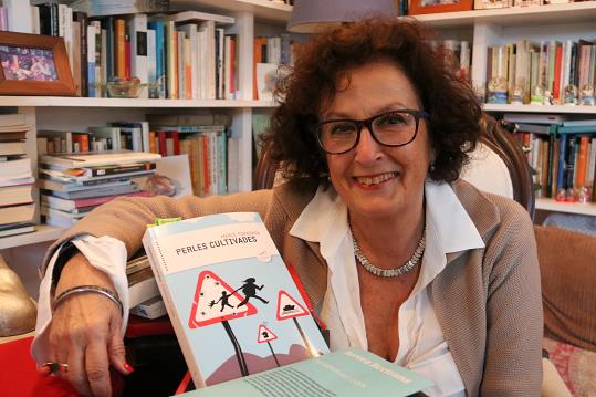 Pla mig de l'escriptora Mercè Foradada, mirant a càmera somrient mentre abraça la novel·la 'Perles cultivades'. ACN