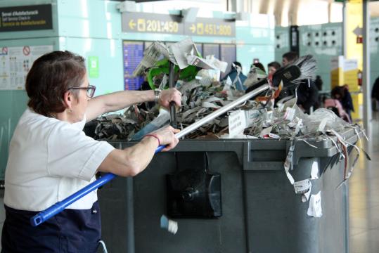 Pla mig d'una treballadora del servei de neteja recollint els papers acumulats a l'aeroport del Prat. ACN