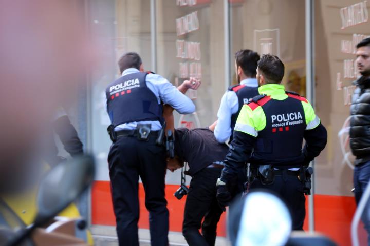 Pla mitjà de dos agents amb un detingut al carrer Nou de la Rambla, on ha acabat la càrrega de Drassanes. ACN