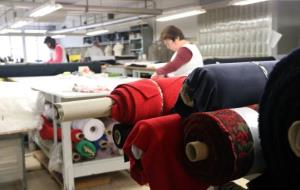 Pla obert d'una treballadora de la fàbrica de Naulover, amb piles de roba en primer pla. Imatge de l'1 de febrer de 2018 . ACN