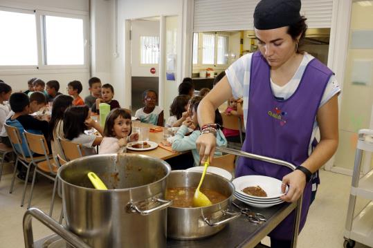 Pla obert on es pot veure una monitora servint menjar al plat al menjador escolar de l'Escola Maria Mercè Marçal de Tàrrega. ACN