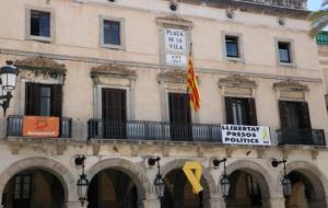 Pla tancat de la zona central de la façana de l'ajuntament de Vilanova i la Geltrú, on s'hi exhibeix un llaç groc i dues pancartes . ACN