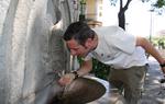 Un home combat la calor bevent una mica d'aigua en una font situada a la Plaça Catalunya de Girona. ACN
