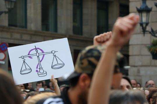 Un interrogant en línia darrere del símbol de la justícia a la manifestació de rebuig a la sentència de La Manada el 26 d'abril de 2018 . ACN