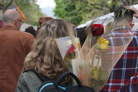 Una dona d'esquena porta dues roses vermelles i una groga a la motxilla. ACN