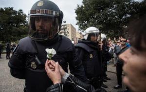 Una dona ofereix una flor a un membre de la policia espanyola davant el centre municipal d'ocupació de Sant Narcís a Girona. ACN