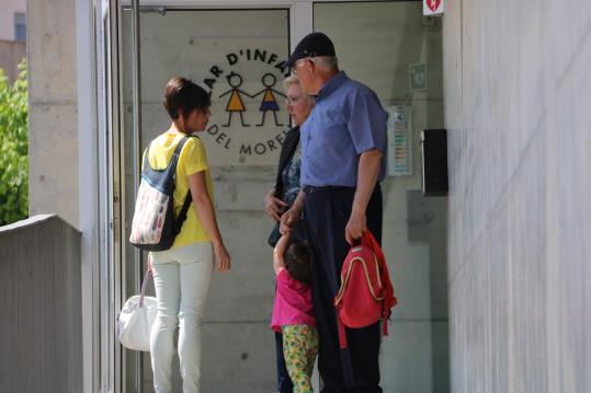 Uns avis amb una nena, d'esquena, parlant amb una dona a la porta de la llar d'infants municipal d'El Morell, aquest 23 de maig de 2017. ACN