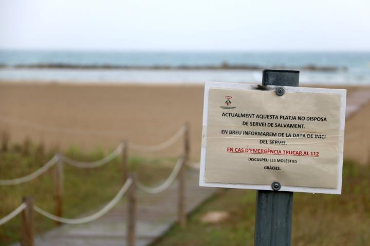 Detall d'un cartell a la platja de la Mota de Sant Pere de Cubelles indicant que el servei de salvament encara no està instaurat. ACN