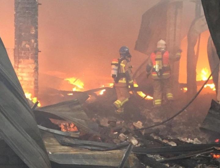 Els bombers treballen per extingir un foc en una nau industrial. Bombers