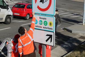 Imatge de dos operaris instal·lant un senyal de la ZBE a l'Hospitalet el 23 de desembre de 2019. ACN