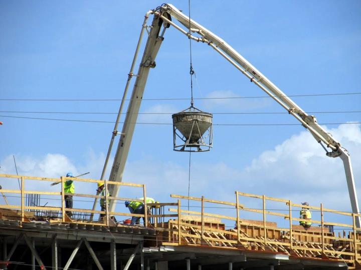 Pla contrapicat d'una grua i operaris treballant en una construcció. ACN