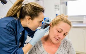 Pla curt d'una infermera inspeccionant l'interior de l'orella d'una pacient. COIB