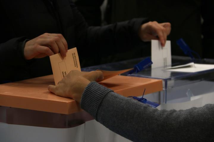 Pla detall d'una mà dipositant les paperetes de les eleccions al Congrés dels diputats i al Senat en una urna. ACN