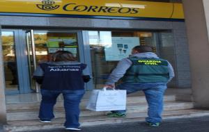 Pla general de dos agents de la Guàrdia Civil i del Servei de Vigilància Duanera a la porta d'una oficina de Correus. Guàrdia Civil