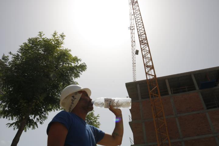 Pla mig d'un operari bebent aigua durant una pausa de la feina a la construcció. ACN