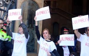 Pla mitjà de diverses dones amb un cartell de 'culpables' sortint de l'Audiència de Barcelona. ACN