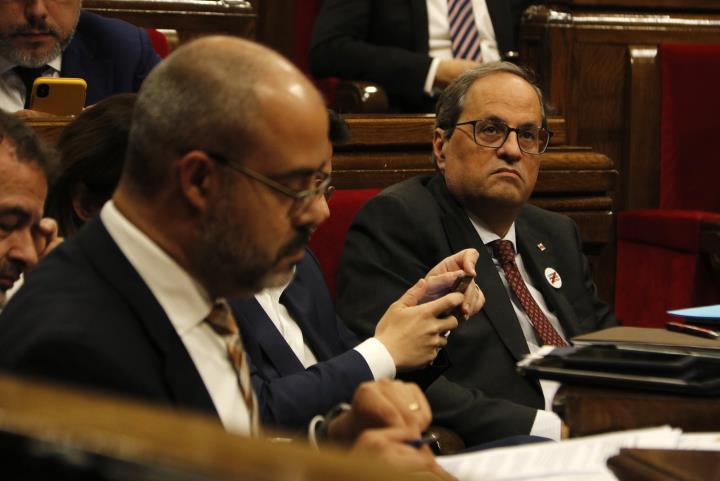 Pla mitjà del president del Govern, Quim Torra, durant el ple del Parlament. En primer pla, desenfocat, el conseller d'Interior Buch. ACN