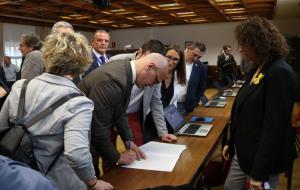 Pla mitjà del senador electe d'ERC Raül Romeva signant un document durant el tràmit de recollida de l'acta de senador acompanyat d'altres senadors rep