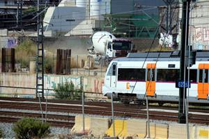 Un comboi de Rodalies circulant pel costat de la futura estació e La Sagrera amb un dels camions que treballen en les obres en segon pla. ACN