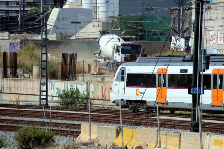 Un comboi de Rodalies circulant pel costat de la futura estació e La Sagrera amb un dels camions que treballen en les obres en segon pla. ACN