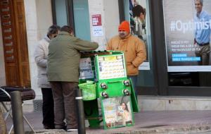 Un venedor de l'ONCE equipat amb una gorra pel fred venent números a uns clients . ACN