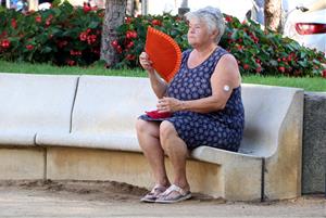 Una dona fent-se vent amb un ventall en una plaça pública de Figueres davant l'onada de calor aquest 2 d'agost de 2018. ACN