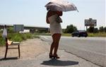 Una noia prostituta a l'N-240 entre Tarragona i Valls, tapant-se amb un paraigua sota un sol de justícia, a l'alçada de la rotonda d'accés a Perafort
