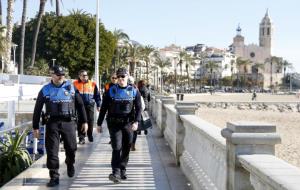 Una parella de policies locals i dos guardes de seguretat privada passegen per la façana marítima de Sitges per dissuadir els manters. ACN