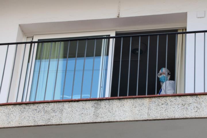 Detall del balcó d'una habitació de la residència Calafell Park de Segur de Calafell, amb un treballador amb EPI sortint per la porta. ACN