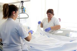 Dues infermeres de l'Hospital del Mar posen bé el llençol a una pacient després d'haver-la recol·locat al llit. ACN