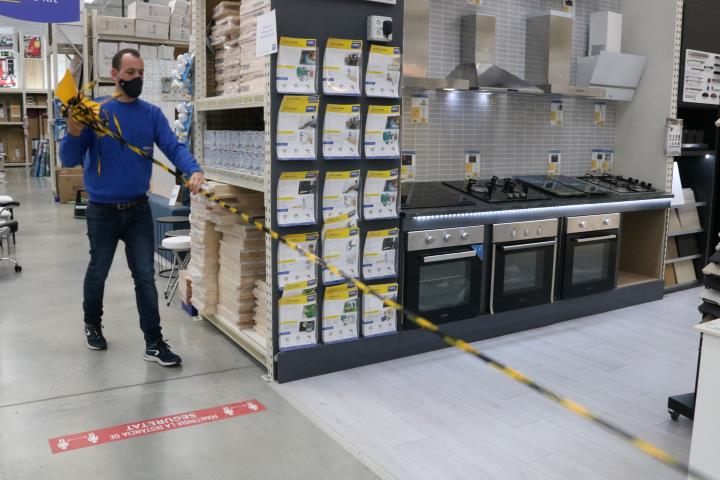 El responsable d'una gran superfície de bricolatge i decoració retirant la cinta amb què es limitava a 800 m2 l'espai de venda. ACN