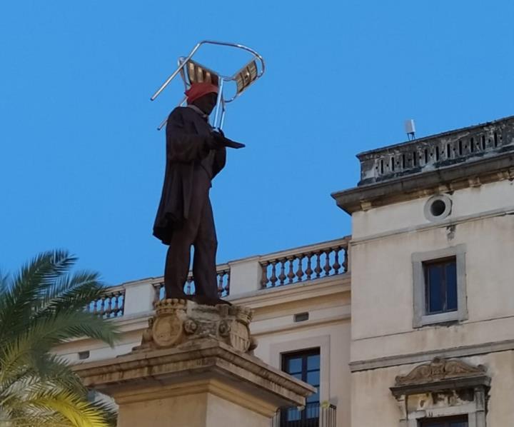 Els bombers retiren una cadira penjada sobre el monument de la plaça de la Vila de Vilanova. EIX