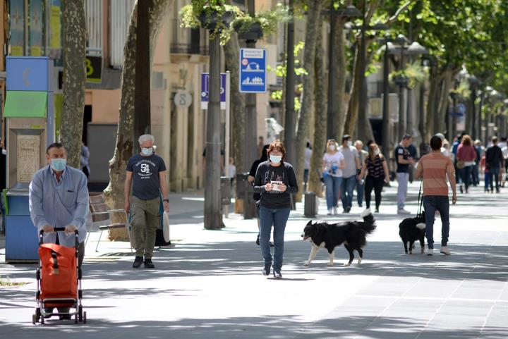 Gent amb mascaretes pel carrer. Eix