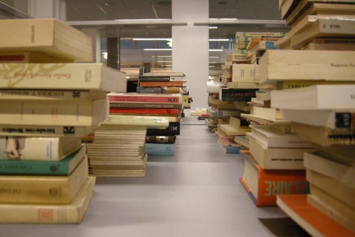 Llibres apilats en una taula a la Biblioteca de la Facultat de Lletres de la UdL. UdL