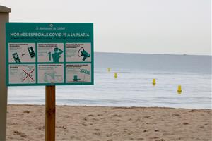 Pla detall d'un cartell amb mesures de prevenció a seguir contra la covid-19 a les platges de Calafell