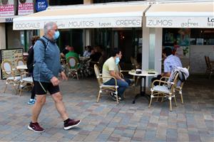 Pla general de la terrassa d'una cafeteria a Calafell Platja mentre un home passeja amb mascareta