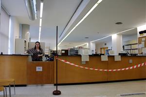 Pla general de l'interior de l'oficina del Registre Civil dels Jutjats de Girona, on la taula principal està separada amb una cinta del punt on s'espe