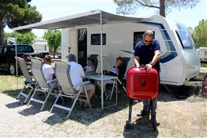 Pla general d'una família desplegant el tendal de la seva autocaravana en l'arribada a un càmping de Sitges, el 12 de juny del 2020