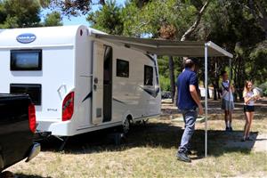 Pla general d'una família desplegant el tendal de la seva autocaravana en l'arribada a un càmping de Sitges, el 12 de juny del 2020