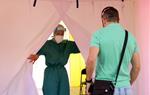 Pla mitjà d'una sanitària obrint una carpa del SEM a Terrassa mentre un noi accedeix a fer-se la prova PCR. ACN