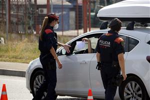 Pla mitjà on es poden veure mossos d'esquadra demanant el certificat laboral per circular al punt de control dels Alamús, el 9 de juliol de 2020. ACN