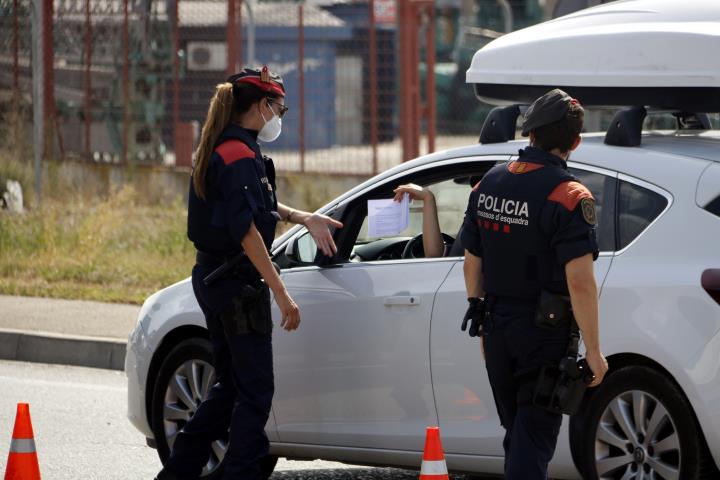 Pla mitjà on es poden veure mossos d'esquadra demanant el certificat laboral per circular al punt de control dels Alamús, el 9 de juliol de 2020. ACN