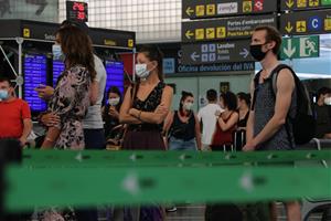 Pla obert de diversos passatgers de l'aeroport del Prat amb mascaretes fent cua per facturar l'equipatge en el dia de la reobertura de la T2. ACN