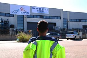 Pla obert d'un treballador de Saint-Gobain d'esquenes i assegut davant del centre logístic de l'empresa al polígon de Bellvei