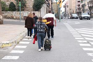 Pla sencer d'uns pares i nens creuant el carrer a la sortida de l'escola Saavedra de Tarragona. Foto del 12 de març del 2020. ACN