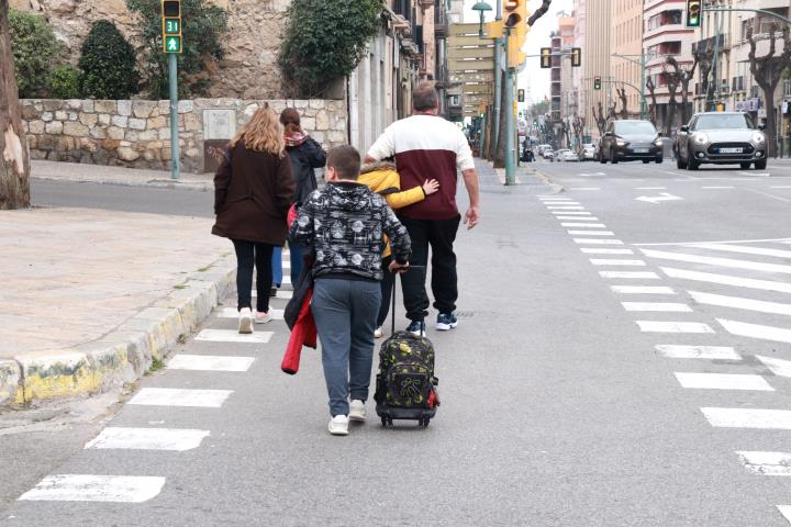 Pla sencer d'uns pares i nens creuant el carrer a la sortida de l'escola Saavedra de Tarragona. Foto del 12 de març del 2020. ACN